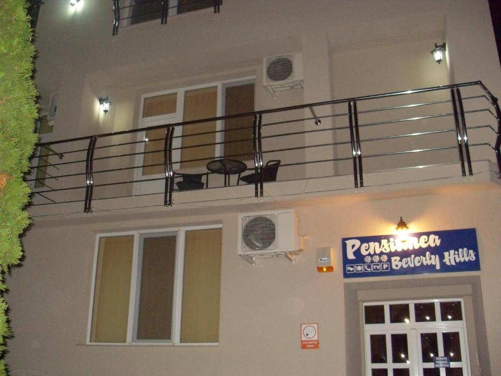 a building with a balcony and a sign on it at Pensiunea Beverly Hills in Baile Felix