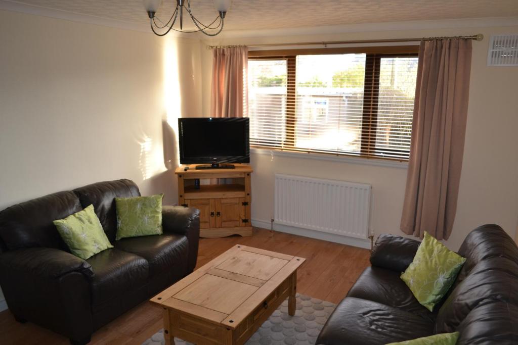 a living room with a leather couch and a tv at Wick Apartment in Wick