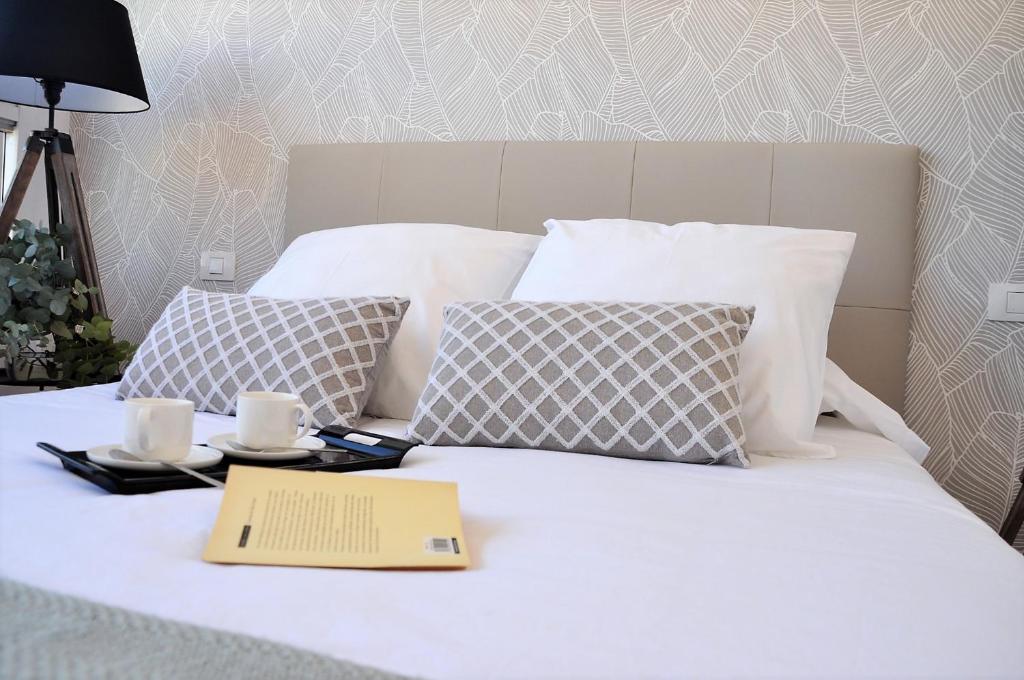 Una cama con un libro y dos tazas. en Apartamento en la Rambla con piscina, en Santa Cruz de Tenerife