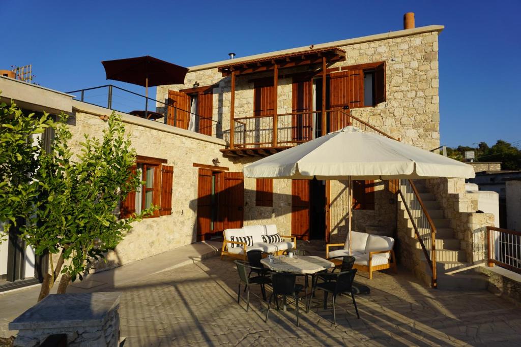 a table and chairs with an umbrella in front of a building at Marmaras in Lyso