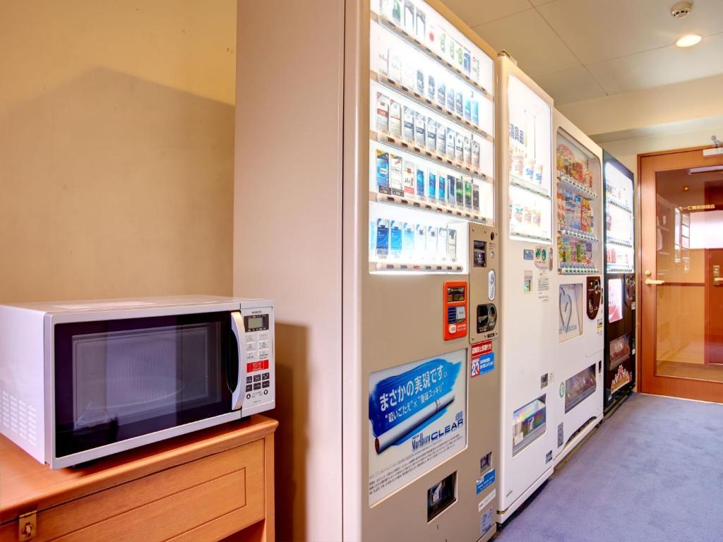 a microwave sitting on a counter next to a wall with posters at Hotel Roco Inn Okinawa in Naha