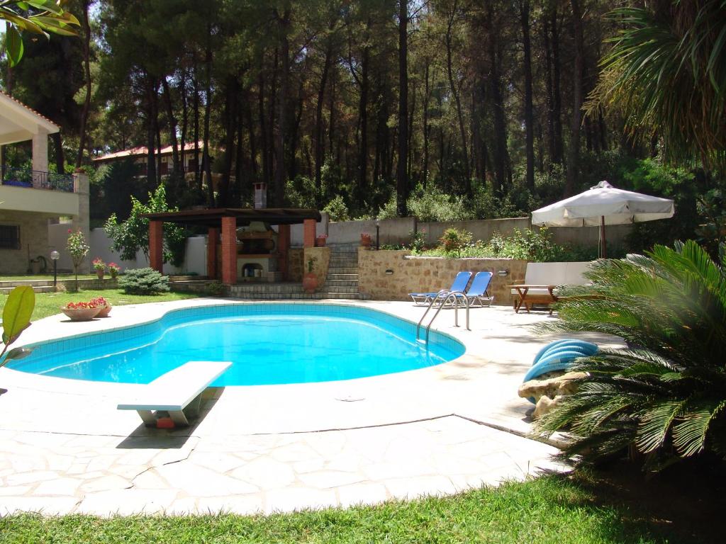 una piscina con patio e ombrellone di Mira Forest Residences a Sani Beach