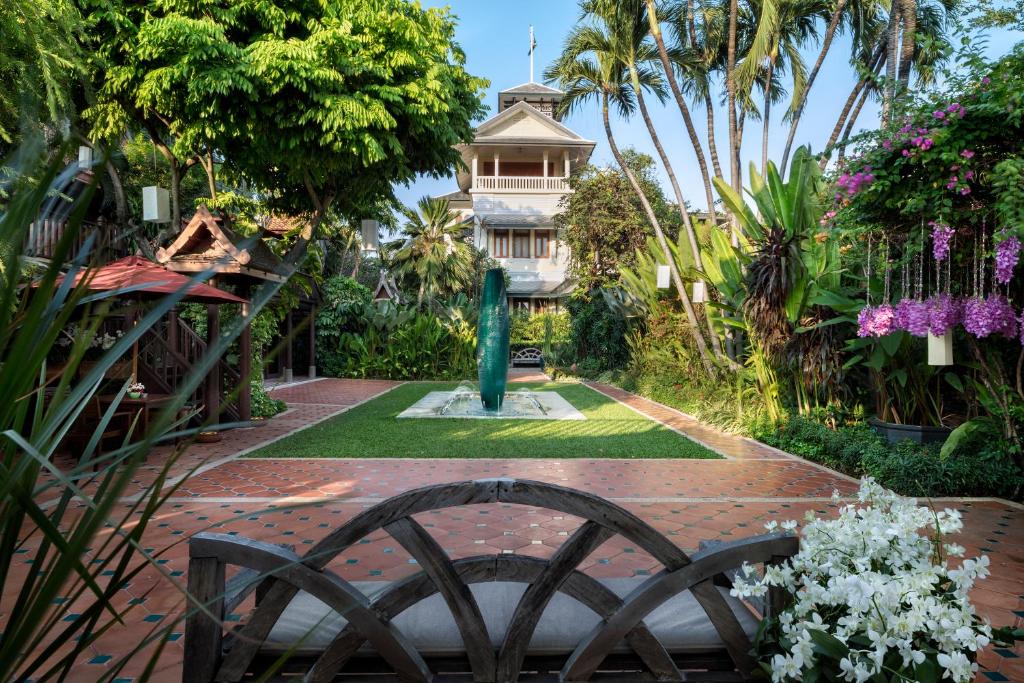 a house with a fountain in the middle of a garden at Chakrabongse Villas in Bangkok