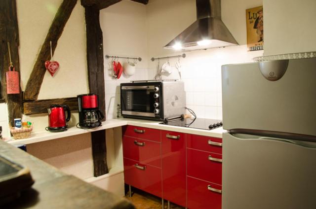 a kitchen with red cabinets and a microwave and a refrigerator at La Maison Rouge in Chinon