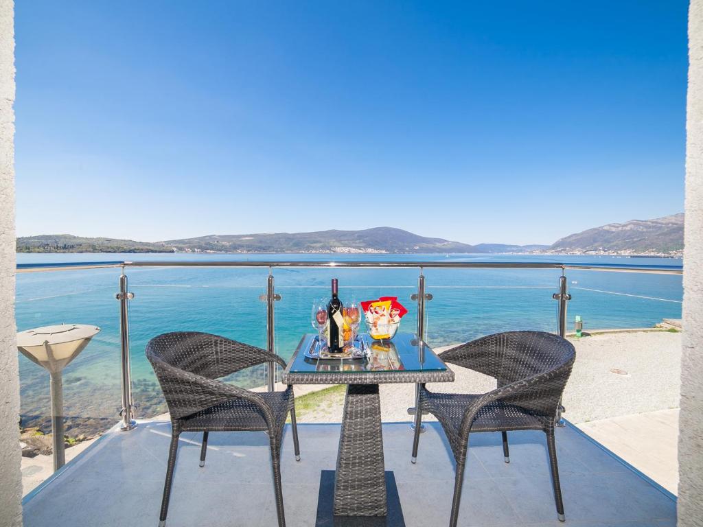 einen Tisch mit Getränken und zwei Stühlen auf einem Balkon mit Meerblick in der Unterkunft Apartments Isja in Tivat