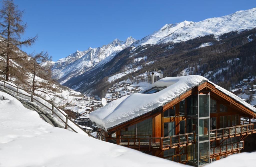 a house with snow on the roof in the mountains at Luxury Chalets & Apartments by Mountain Exposure in Zermatt