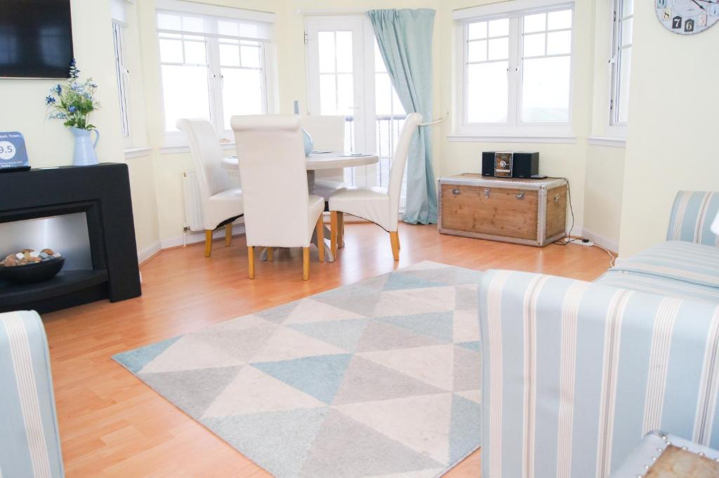 a living room with a fireplace and a table with chairs at Wood Court, Troon in Troon