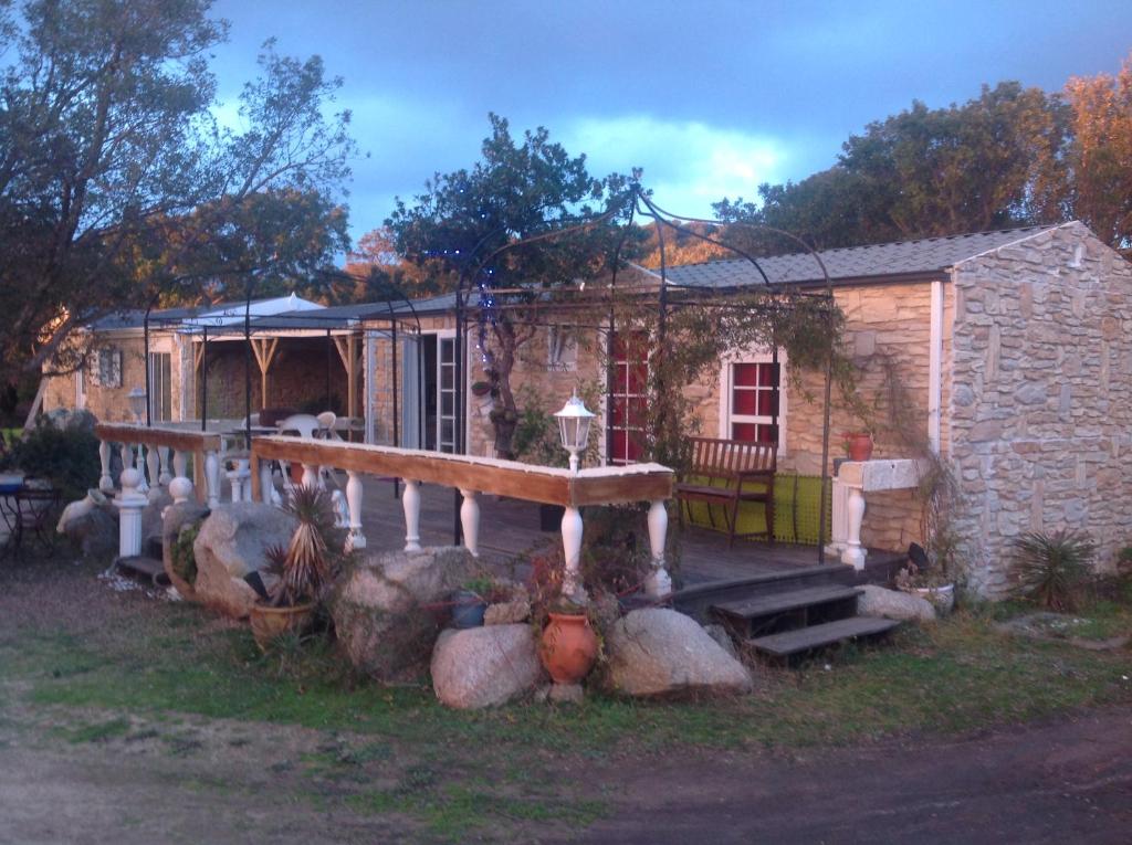 uma pequena casa de pedra com um alpendre e um edifício em Chalet Valle di Corti em Pianottoli-Caldarello