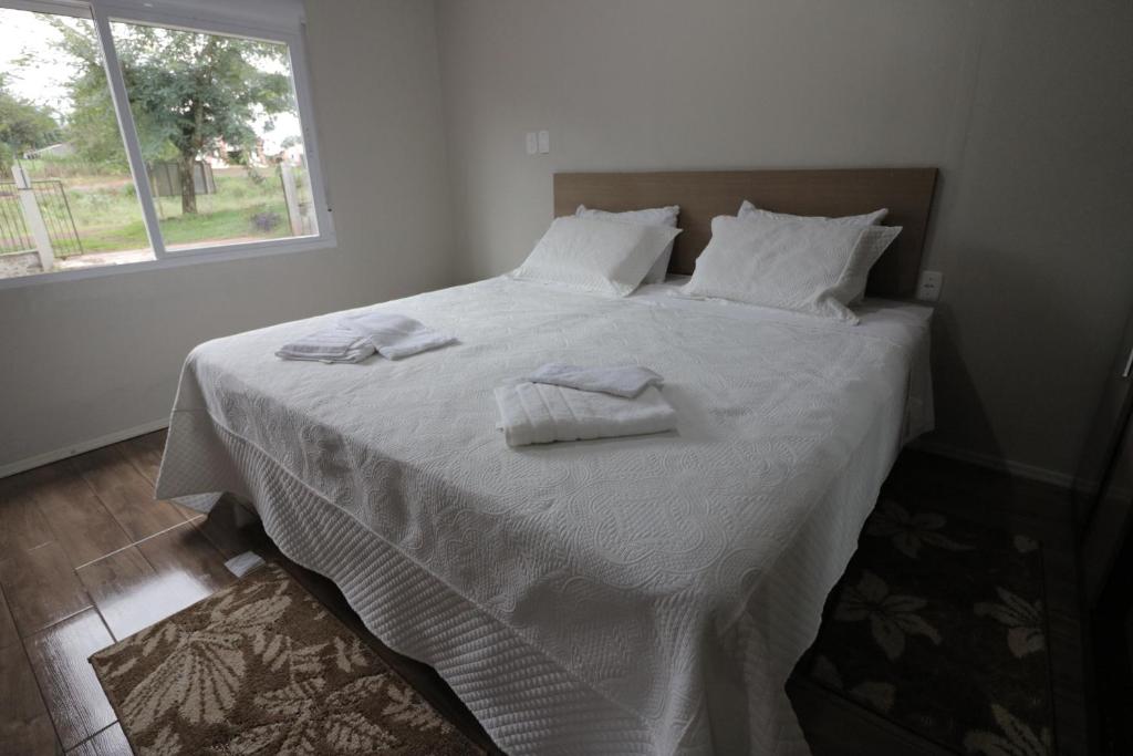 uma cama branca com toalhas brancas em cima em O Rancho em Palmeira das Missões