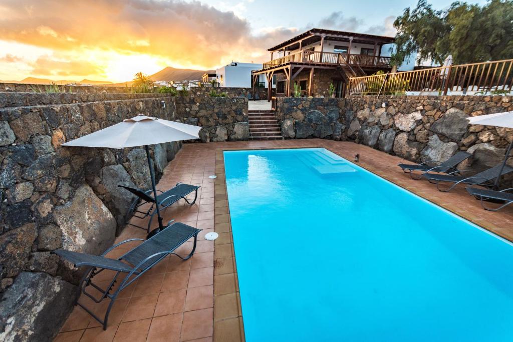 uma piscina com cadeiras e um guarda-sol e uma casa em Villa Alcalde em Mácher