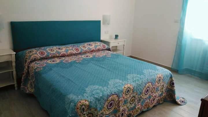 Casa Nova b&b في ألغيرو: غرفة نوم بسرير ولحاف ازرق
