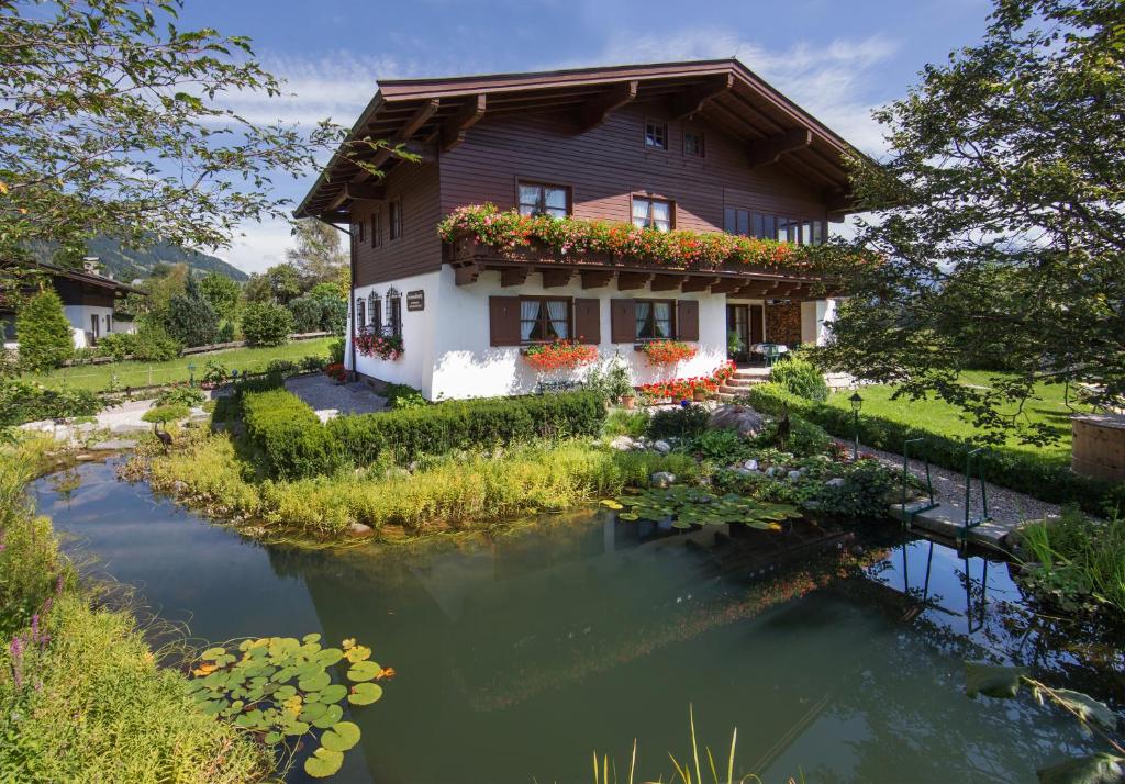 ein Haus mit einem Teich davor in der Unterkunft Ferienhaus Mandl Garten Sauna Hot Pot Pool in Maishofen