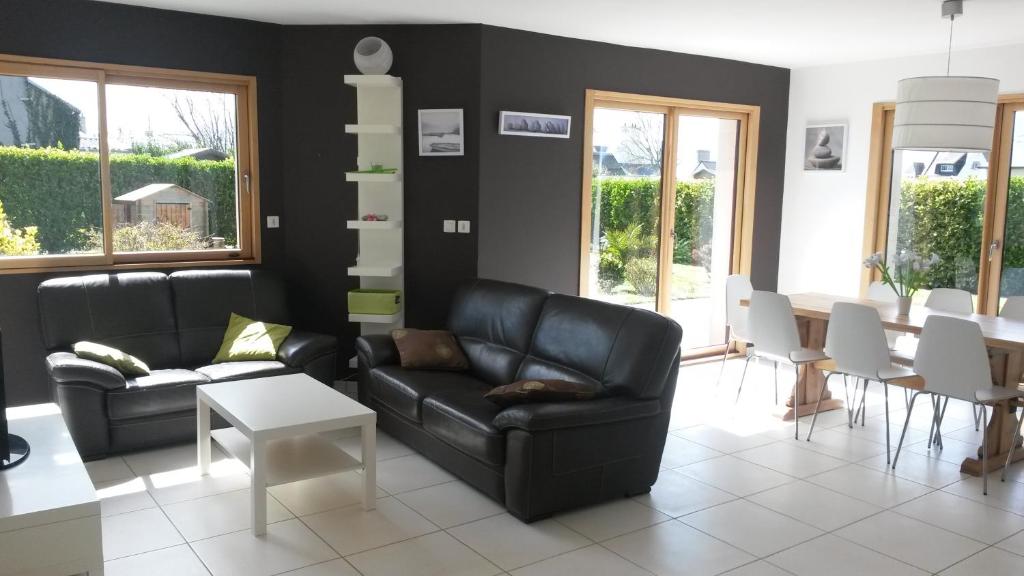 ein Wohnzimmer mit einem schwarzen Ledersofa und einem Tisch in der Unterkunft Villa Lampaul in Lampaul-Plouarzel