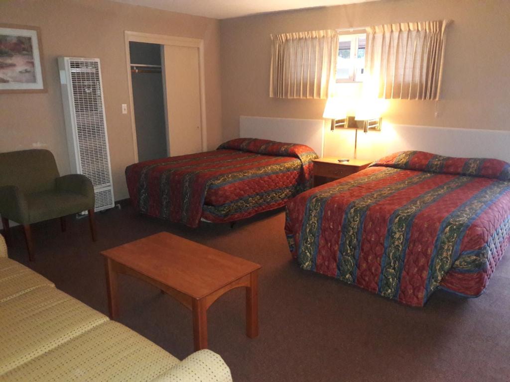 a hotel room with two beds and a table at Monroe Motel in Monroe