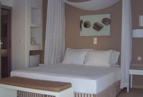 a bedroom with a large bed with white sheets at Mar Inn Hotel in Chora Folegandros