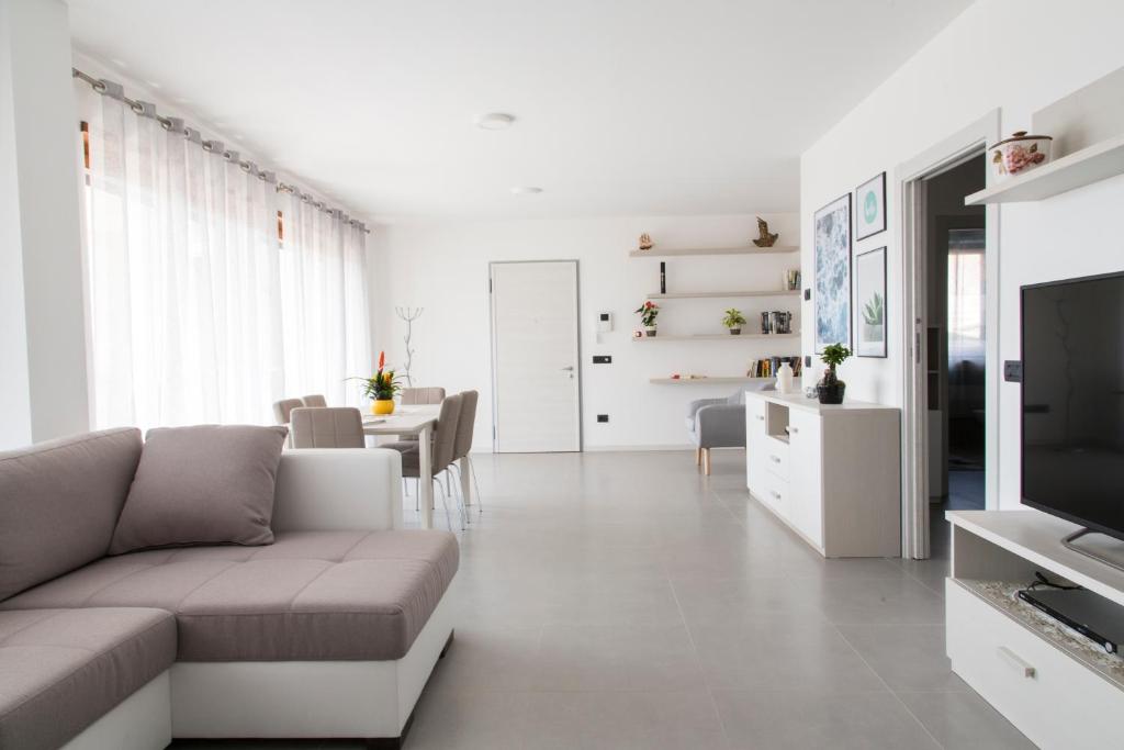 a white living room with a couch and a table at La terrazza sul lago in Pergine Valsugana