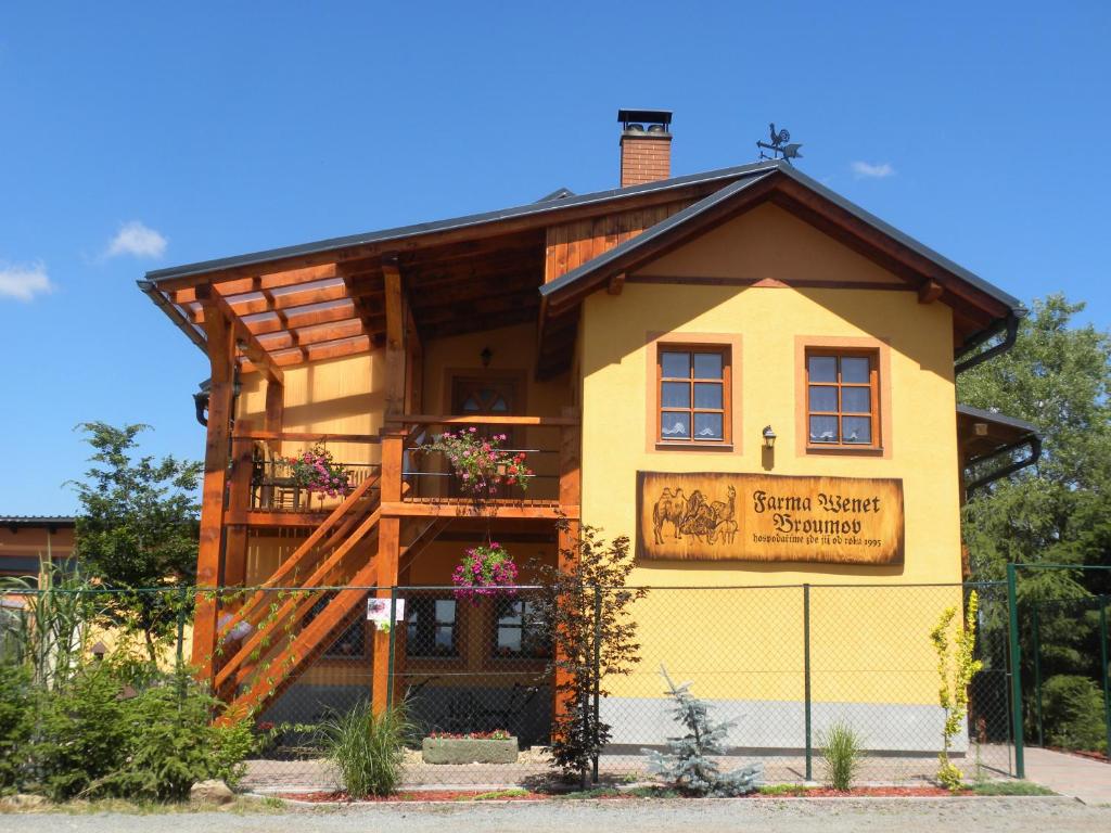 un piccolo edificio giallo con un cartello sopra di Farma Wenet a Broumov