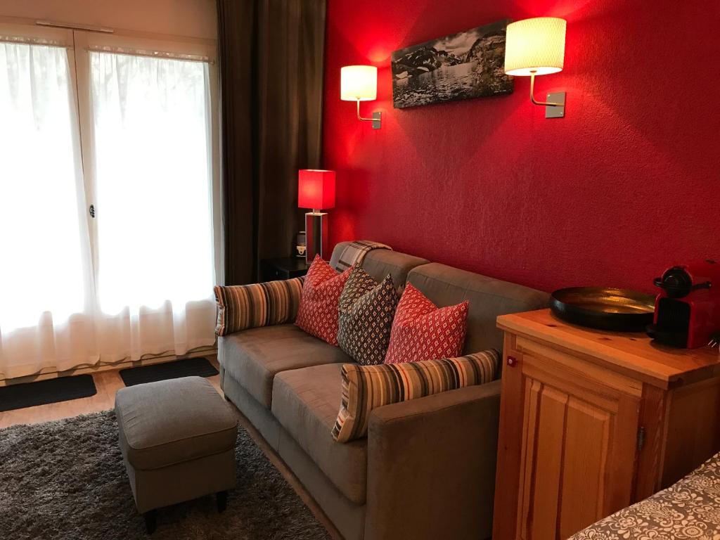 a living room with a couch and a red wall at Le Grand Panorama No11 in Saint-Gervais-les-Bains