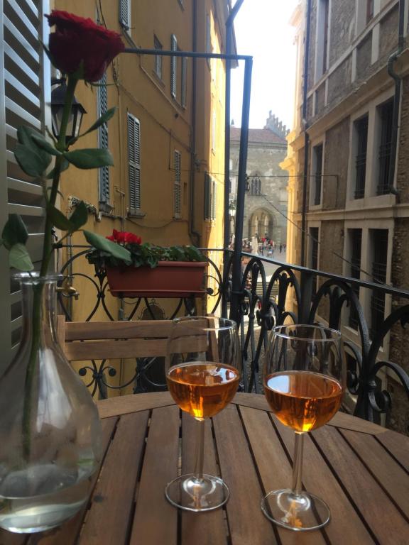 two wine glasses sitting on a wooden table on a balcony at Casa Vacanze Piazza Vecchia in Bergamo