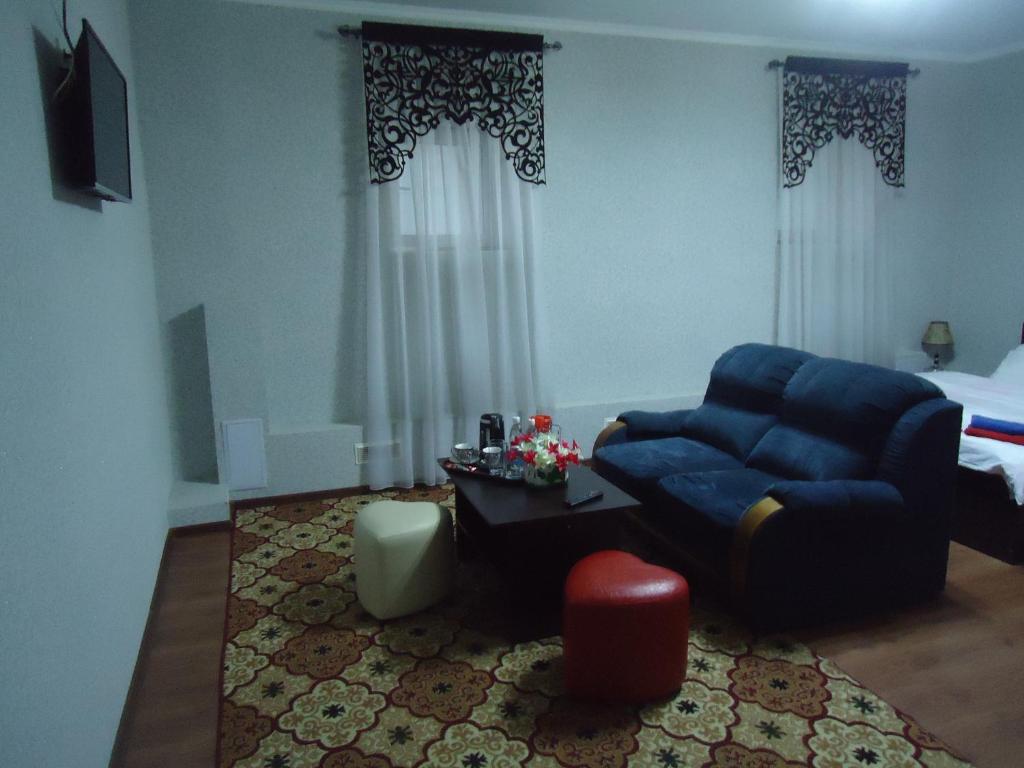 sala de estar con sofá azul y cama en Tumar en Bishkek