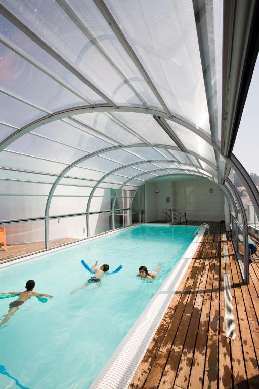 three people swimming in a swimming pool on a ship at Hotel Praia in Nazaré