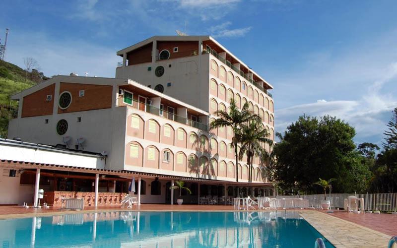 a building with a swimming pool in front of a building at Aparts -Hotel Cavalinho Branco in Águas de Lindóia