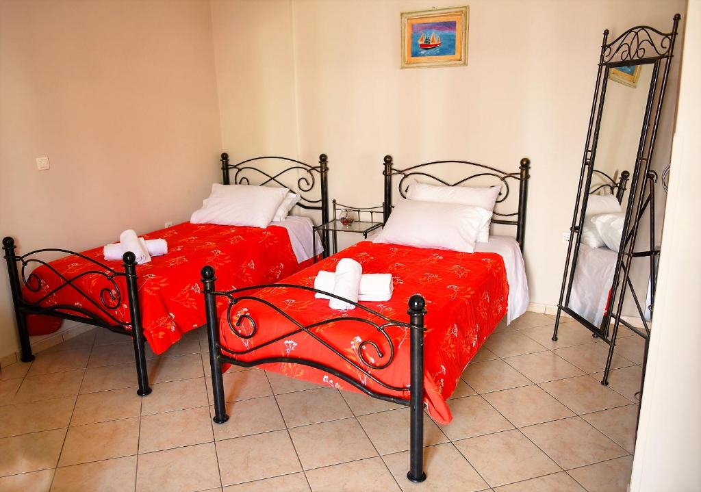 Duas camas individuais com lençóis vermelhos num quarto em Aella Studios em Panagioúda