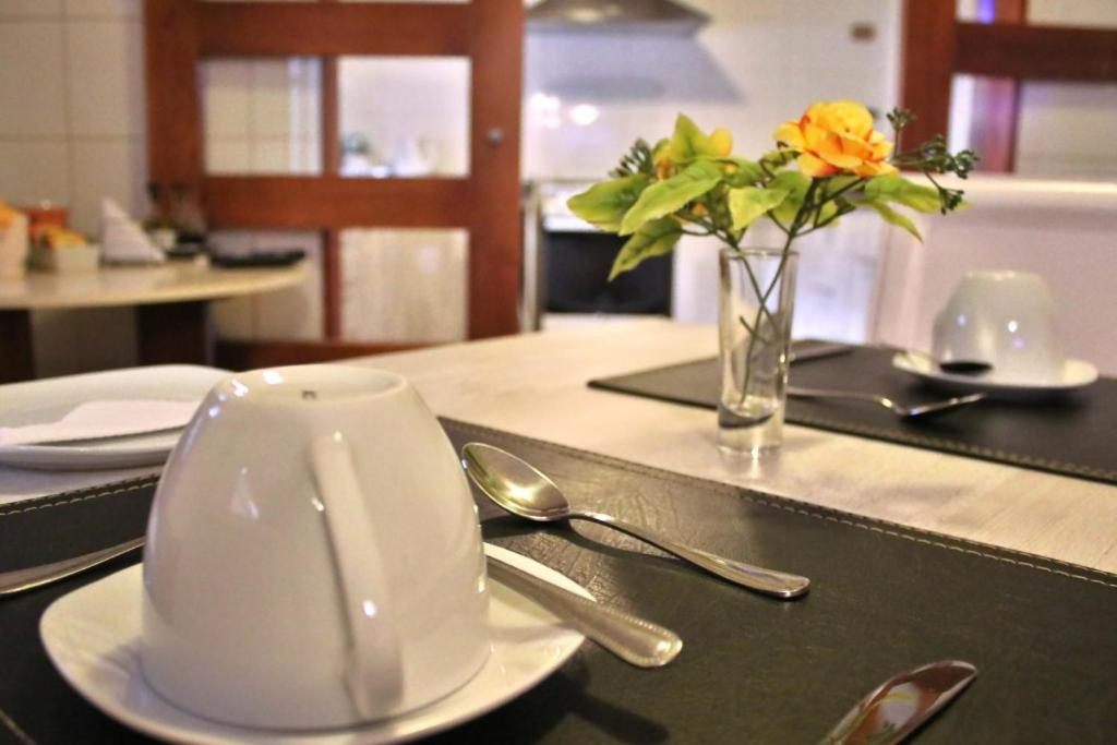 una mesa con una taza de café blanca y un jarrón de flores en Hostal Itaf, en Arauco