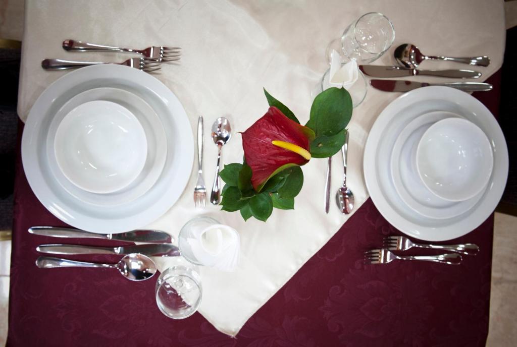 a table with two white plates and a red flower on it at Victoria Hotel in Jerusalem