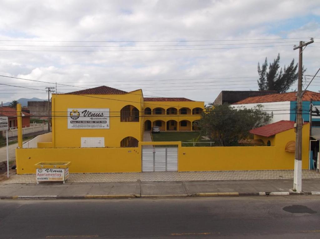 um edifício amarelo no lado de uma rua em Vênus Apartamentos em Ilha Comprida