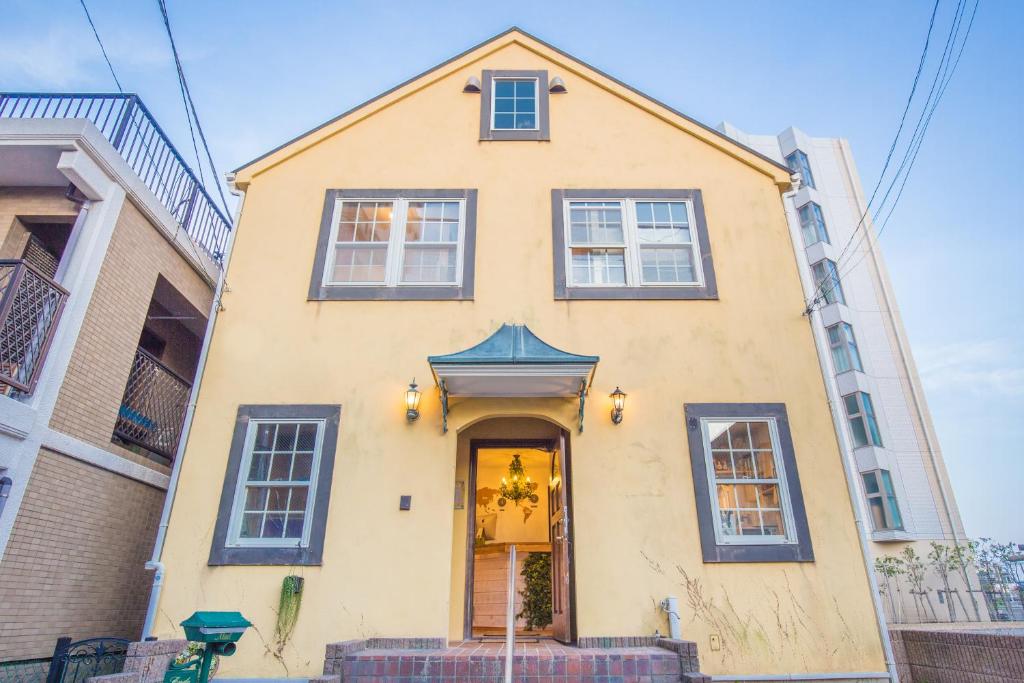 a yellow house with a front door on a street at IZA Enoshima Guest House and Bar in Fujisawa