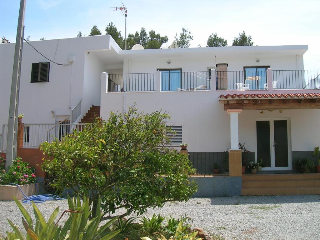 een wit huis met een balkon erop bij Pensión Las Tres Golondrinas in Es Figueral Beach