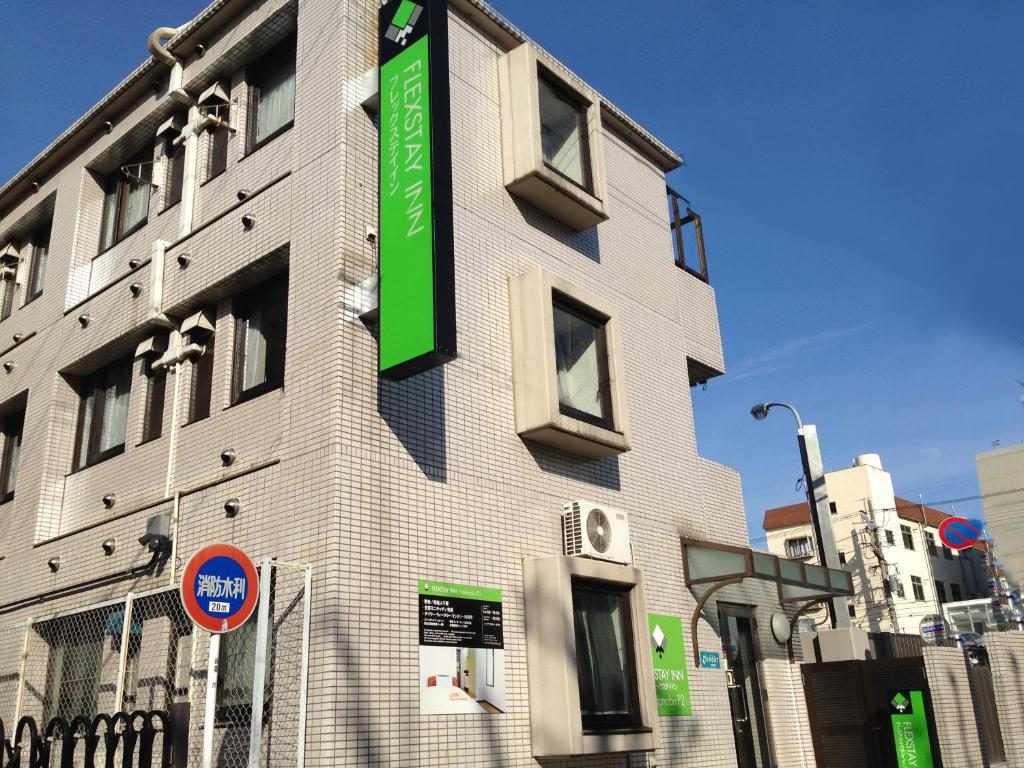 un bâtiment avec un panneau vert sur son côté dans l'établissement FLEXSTAY INN Nakanobu, à Tokyo