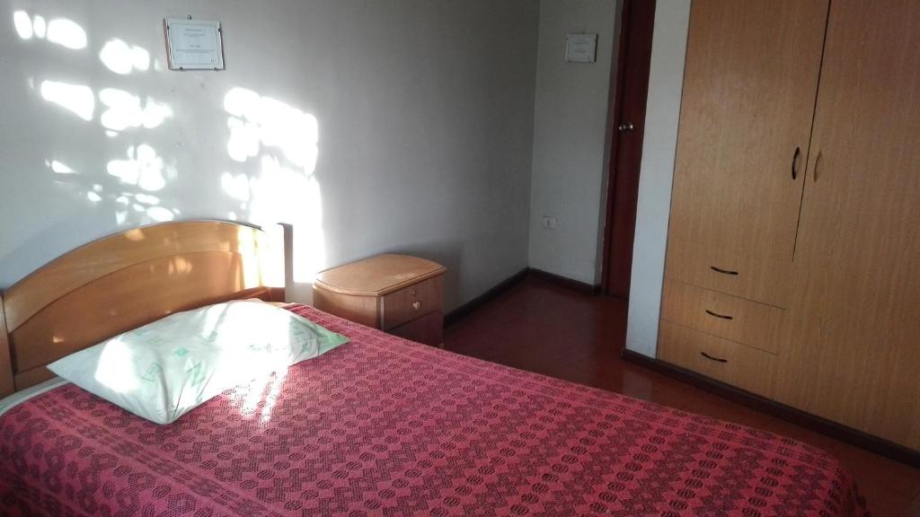 a bedroom with a bed with a red comforter at Hostal Killaymi in Arequipa