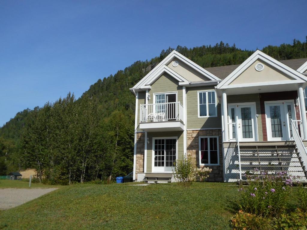 a large house with a hill in the background at Condo Mont-Edouard in LʼAnse-Saint-Jean