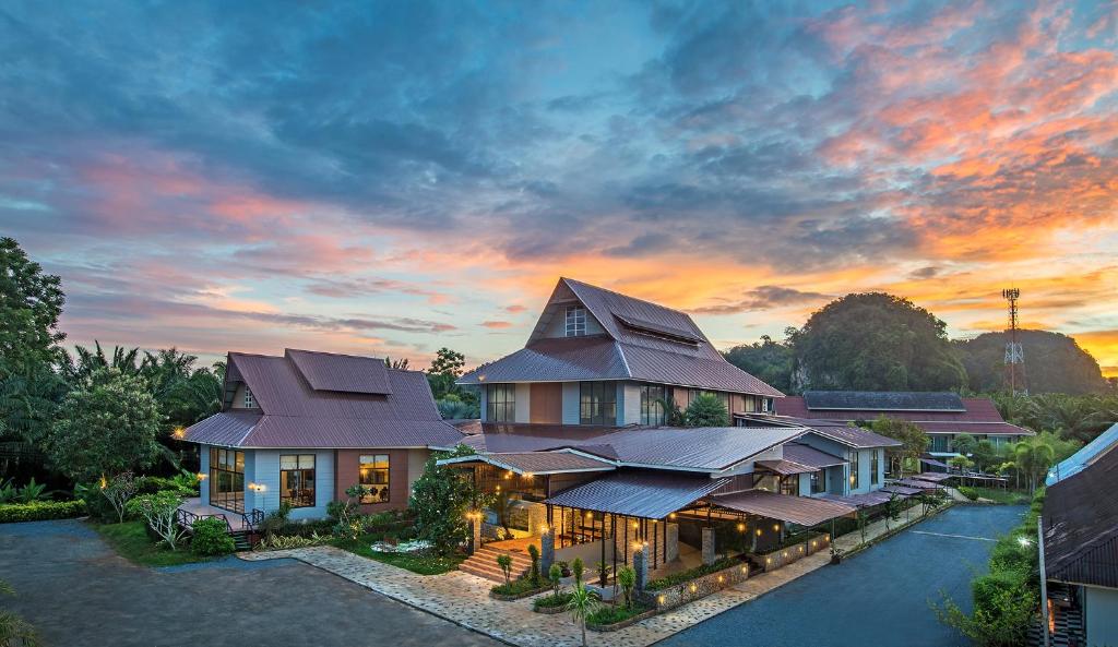 a house with a roof with a sunset in the background at Krabi Home Town Boutique in Krabi
