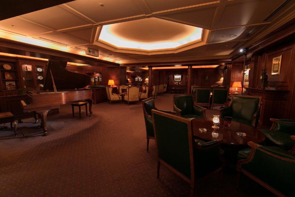 a room with a piano and a table and chairs at Hotel Nikko Fukuoka in Fukuoka