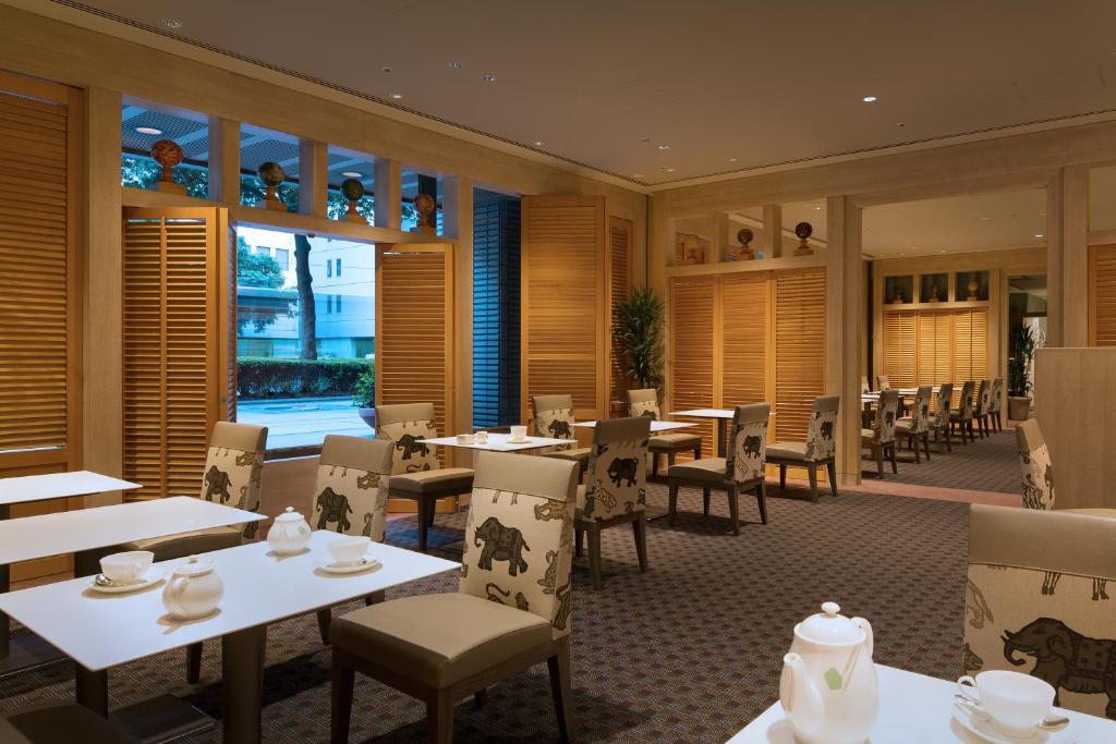 a restaurant with white tables and chairs and windows at Hotel Nikko Fukuoka in Fukuoka