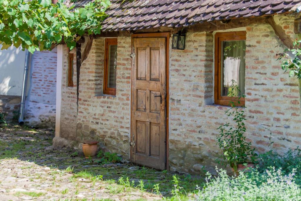 une vieille maison en briques avec une porte en bois dans l'établissement Dominic Boutique, Little Barn , Cloasterf, à Cloaşterf