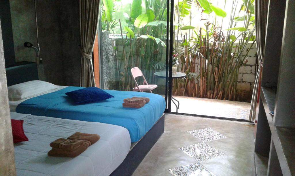 a bedroom with a bed with blue sheets and a balcony at Baan Bida in Krabi town