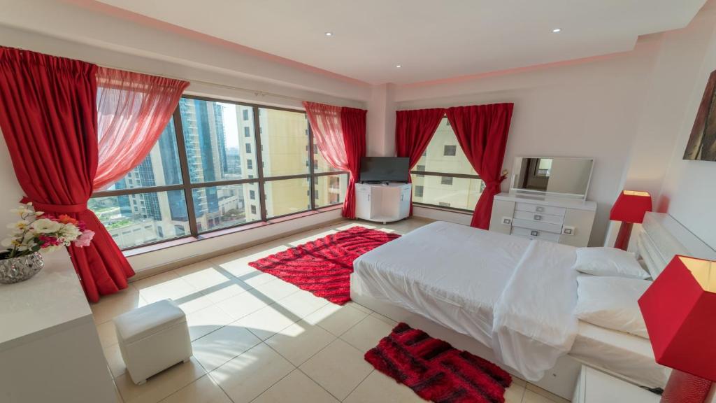 a bedroom with red curtains and a bed and a television at Jbr Beach Walk Rimal 3 in Dubai