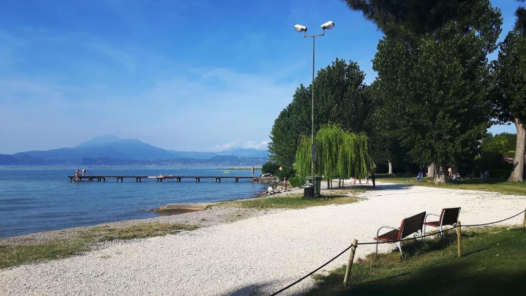 two benches on a beach next to the water at Casa Patrizia B&B cir in info in Sirmione