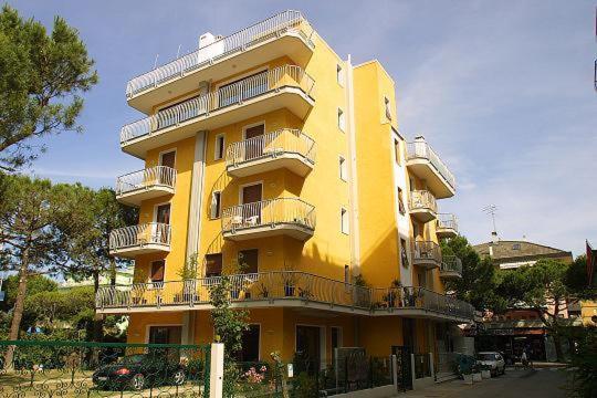 un edificio amarillo con balcones en un lateral en Residence Mini Sayonara, en Lido di Jesolo