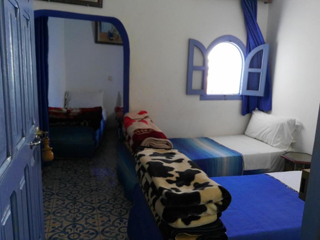 a room with two beds and a window in a room at Hotel Ouarzazate in Chefchaouene