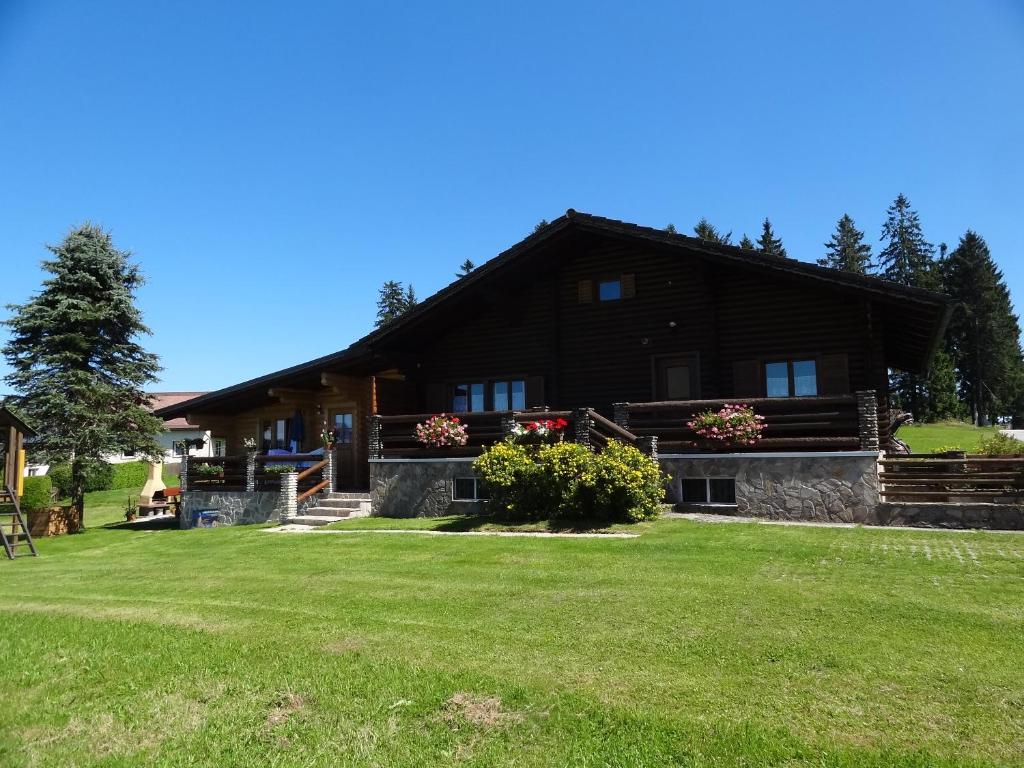 une grande maison en bois avec une pelouse dans l'établissement Blockhaus-Bärnkopf, à Bärnkopf