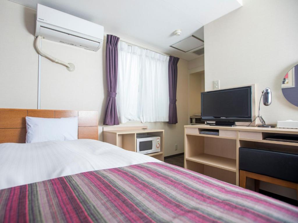 a hotel room with a bed and a flat screen tv at FLEXSTAY INN Shinagawa in Tokyo