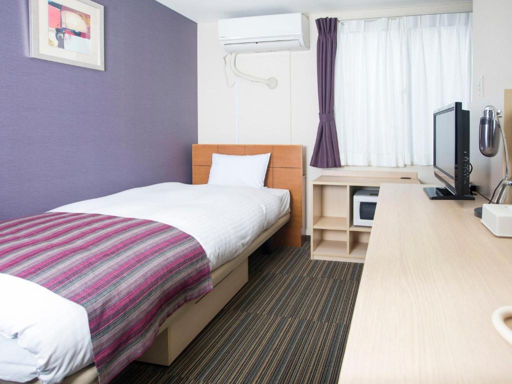a hotel room with a bed and a flat screen tv at FLEXSTAY INN Shinagawa in Tokyo