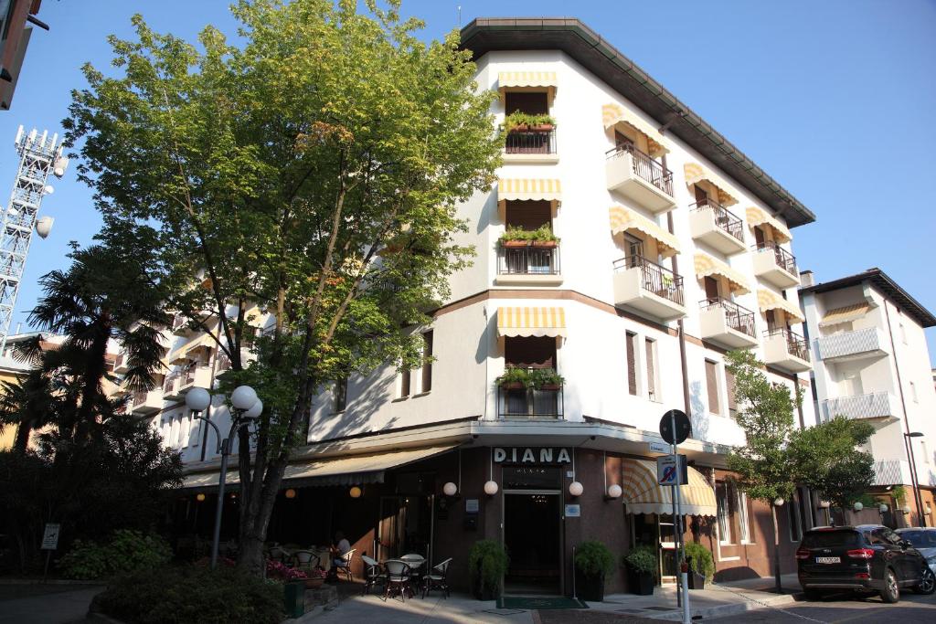 un grand bâtiment blanc avec des boîtes de fleurs sur ses fenêtres dans l'établissement Hotel Diana, à Grado