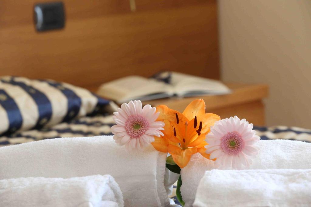 een vaas gevuld met bloemen op een bed bij Hotel Costabella in San Zeno di Montagna