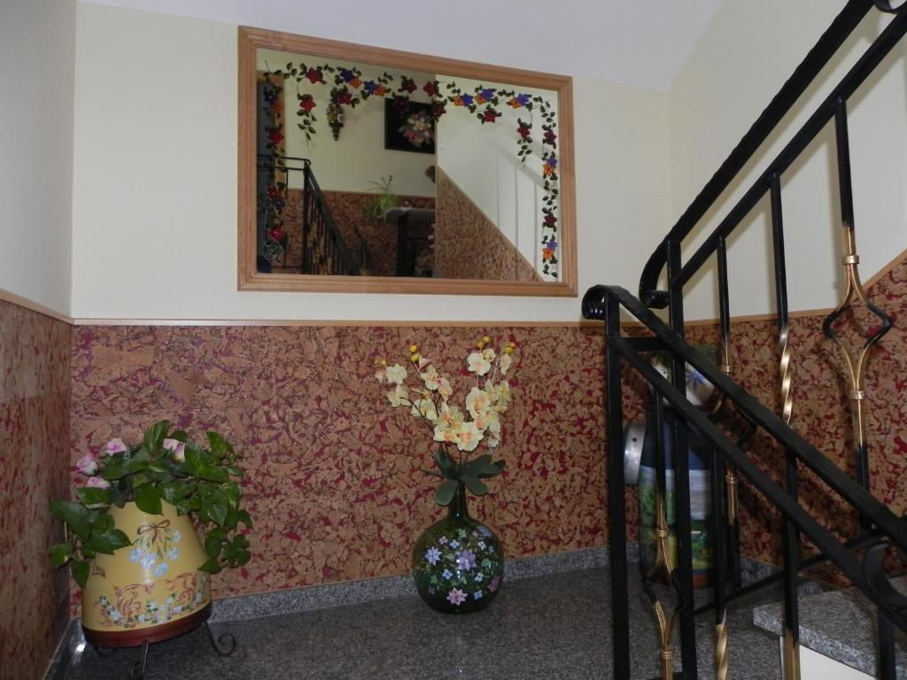 a staircase with a vase of flowers and a mirror at O Lar de Carmiña in Devesa